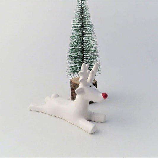 White ceramic reindeer with a red nose on a light gray background